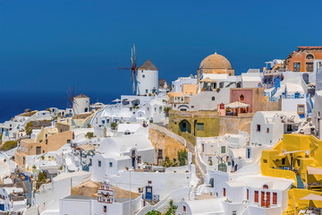 Wall Mural - Traditional windmills and white buildings dominate the northern edge of the village of Oia, Santorini in summertime