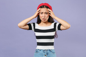 Poster - Preoccupied sick tired young brunette asian woman 20s wearing casual striped t-shirt red beret standing put hands on head looking camera isolated on pastel violet colour background studio portrait.