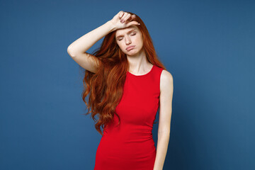 Wall Mural - Exhausted tired dissatisfied young redhead woman 20s wearing bright red elegant evening dress standing put hand on head keeping eyes closed isolated on blue color wall background studio portrait.