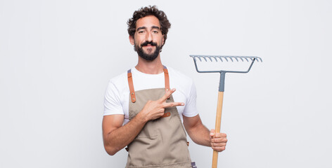 Wall Mural - young man feeling happy, positive and successful, with hand making v shape over chest, showing victory or peace