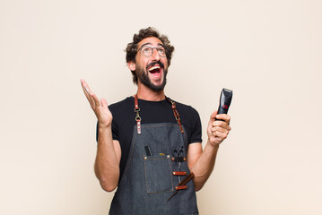 Wall Mural - young man feeling happy, amazed, lucky and surprised, celebrating victory with both hands up in the air