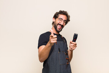 Wall Mural - young man smiling with a positive, successful, happy attitude pointing to the camera, making gun sign with hands