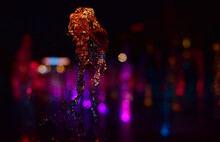Close-up Of Splashing Water Against Illuminated Lights At Night