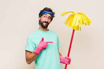 Wall Mural - young man smiling, feeling happy, carefree and satisfied, pointing to concept or idea on copy space on the side