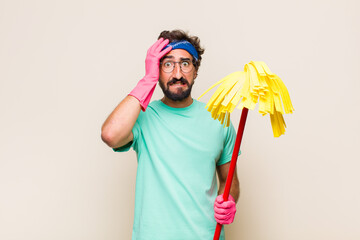 Wall Mural - young man feeling horrified and shocked, raising hands to head and panicking at a mistake