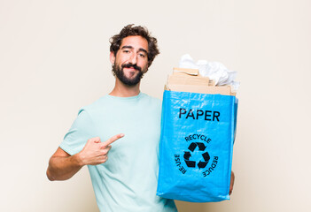 Wall Mural - young man smiling happily and pointing to side and upwards with both hands showing object in copy space