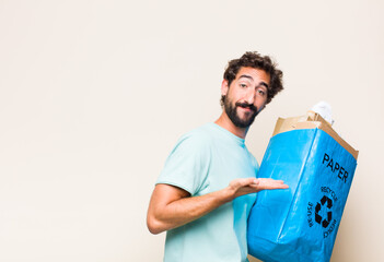 Wall Mural - young man feeling happy and smiling casually, looking to an object or concept held on the hand on the side