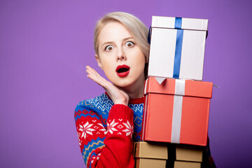 Poster - Beautiful woman in Christmas sweater with gift box on purple background