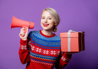 Wall Mural - Beautiful woman in Christmas sweater with gift box and megaphone o