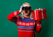 Beautiful woman in Christmas sweater holds gift box and binoculars