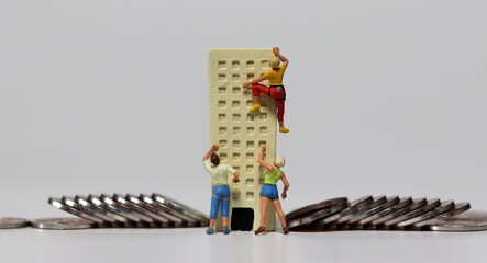 Wall Mural - Miniature people trying to climb a miniature building with coins. The concept of deepening job shortages.
