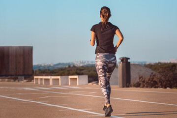 Young fitness woman runner athlete running on the road. Sport tight clothes. Fitness and workout wellness concept