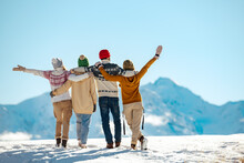 Happy Friends Embracing Against Snow Capped Mountains