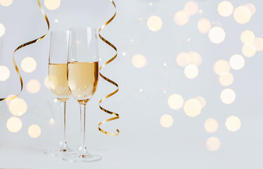 Wall Mural - Two glasses of champagne with lights and ribbons on a white background holiday