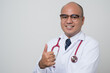 © Chanakon - Doctor in white coat, stethoscope cross his arm and thumb up look into.camera with smile beside corner isolated on white background.