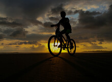 Silhouette Girl Riding Bicycle On Road During Sunset