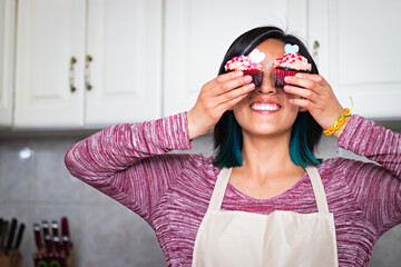 A smiling woman with two cupcakes