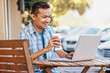 © SuperStock - Malaysian man drinking coffee and using laptop at cafe
