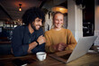 © StratfordProductions - Handsome young man with beautiful woman looking at laptop screen in cafe and drinking coffee