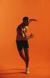 © Jacob Lund - Muscular athlete working out on orange background