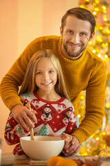 Wall Mural - Girl and her dad stirring something in a bowl and smiling