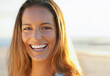 © SuperStock - Portrait of healthy beautiful young woman at the beach and smiling