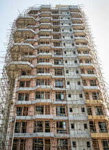 Modern Highrise Building Under Construction Surrounded By Bamboo Scaffolding