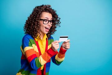 Poster - Photo of attractive young curly hair girl hold credit card excited surprised happy isolated over blue color background