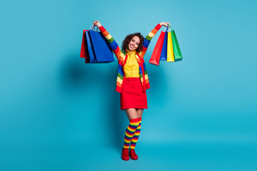 Full body photo of happy curly hair woman wear skirt carry bags buy things shopping isolated over blue color background