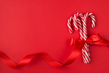 Tasty surprise for Christmas concept. Top above overhead close up flatlay photo of hard candy canes wrapped with bright ribbon isolated over bright color table