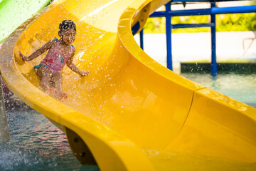 Cute little girl in swimming suit playing waterslide at waterpark.