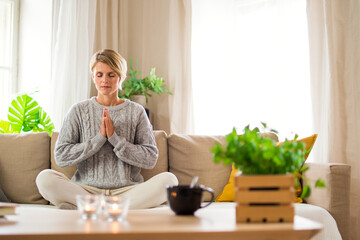 Portrait of woman indoors at home doing yoga, mental health and meditation concept.