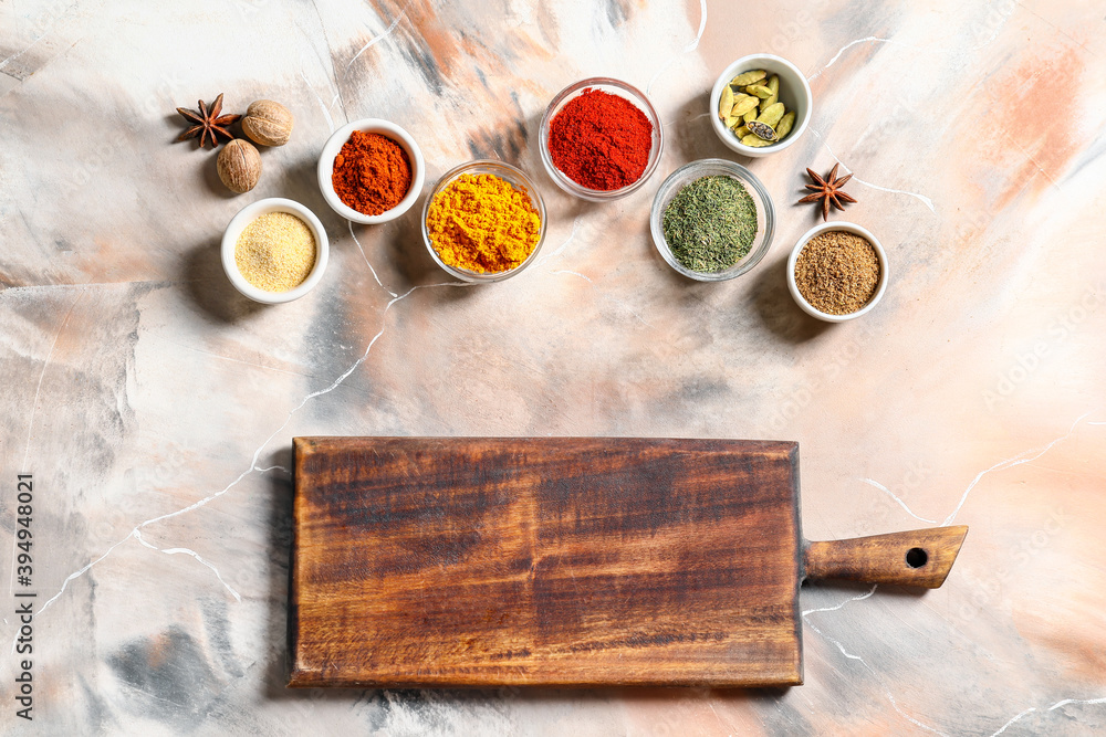 Wooden cutting board with spices on light background