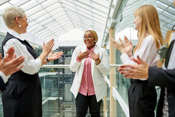 business team welcome a new african employee to the company, clapping hands in the hall, smile