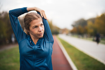 Wall Mural - Beautiful adult woman is exercising outdoor on cloudy day in autumn.