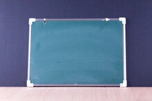 Close-up Of Blank Blackboard On Table Against Wall