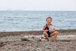 © Angelina - Little girl in a swimsuit sits on a log on the beach and eats cookies