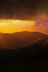 Wall Mural - Dramatic sunset sky with clouds over mountain ridge.