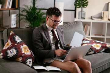 Wall Mural - Businessman with no pants working at home. Young man using the laptop having video call. 