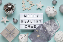 Christmas Background, Silk Handmade Medical Mask And Lightbox With Text Merry Healthy Xmas. Flat Lay. Covid-19 New Year Concept.