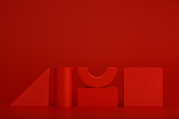 Wall Mural - Red monochromatic still life with three-dimensional red geometric figures on a red background with a space for text