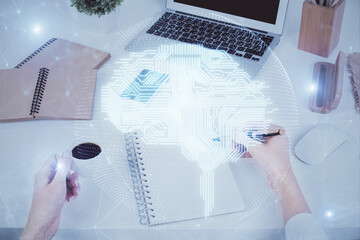 Double exposure of woman's writing hand on background with brain hud. Concept of learning.