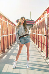 Wall Mural - Urban portrait of a young skater woman holding a longboard skateboard.