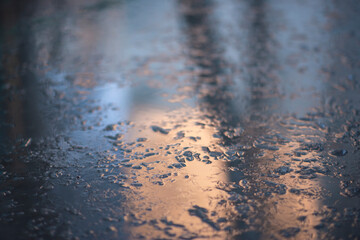 Frozen water in a puddle. Sunlight reflects off the frozen surface of the puddle. Natural phenomenon, abstract background.