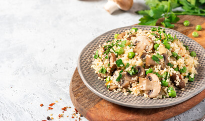 Sticker - Couscous with fried mushrooms, onions, green peas, and parsley in a plate on a grey background. Copy space for text. Tasty vegan couscous salad with champignons.