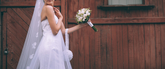 Young bride wearing vintage wedding dress posing next to the red barn. Wedding photography and concept.