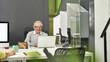 © Svitlana - Aged man, senior intern looking happy while typing, using laptop, sitting at desk, working in modern office