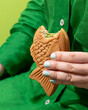 canvas print picture - Green scene oh woman in dress holding a bitten matcha Taiyaki
