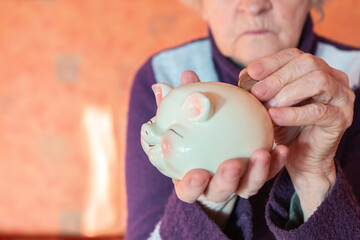 Old woman holding piggy bank and coins