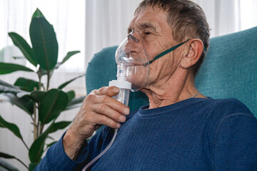 elderly senior sits in a armchair with an oxygen mask in quarantine at home